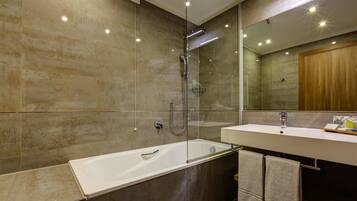 A modern bathroom with a glass-enclosed shower, a white bathtub, and a vanity with a mirror and sink.