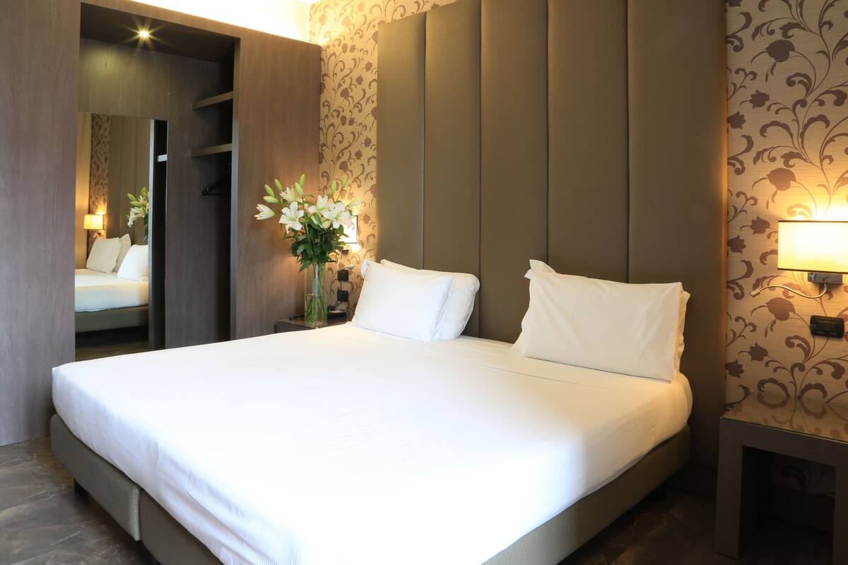 A neatly made bed with white linens in a modern hotel room.