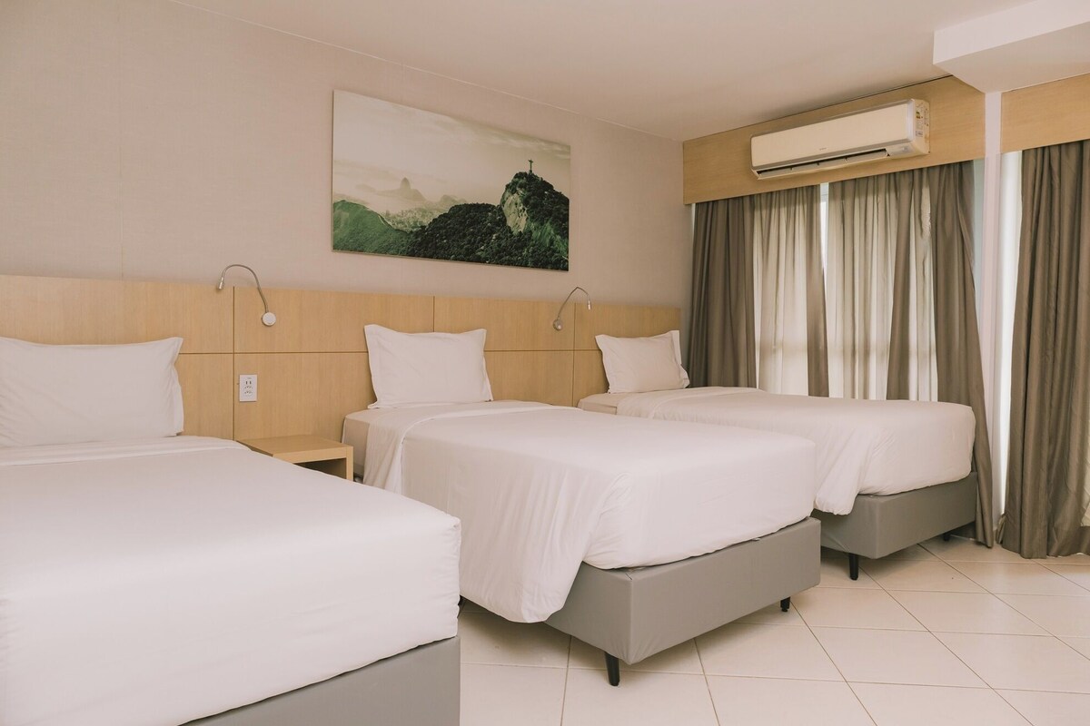 A hotel room with two beds, a painting on the wall, an air conditioning unit, and curtains.