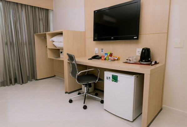 Une chambre d’hôtel équipée d’un bureau, d’une chaise, d’une télévision et d’un mini-réfrigérateur.