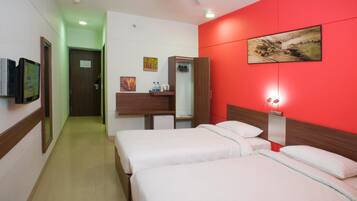 A hotel room with two beds, a desk with a chair, a wardrobe, a television, and a painting on the wall.