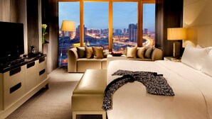 A hotel room with a large bed, a sofa, a TV, and a view of a cityscape. - Banyan Tree Tianjin Riverside (Tianjin)