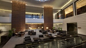 A modern lobby with a central seating area, a high ceiling with a skylight, and a second-floor balcony. - Banyan Tree Tianjin Riverside (Tianjin)