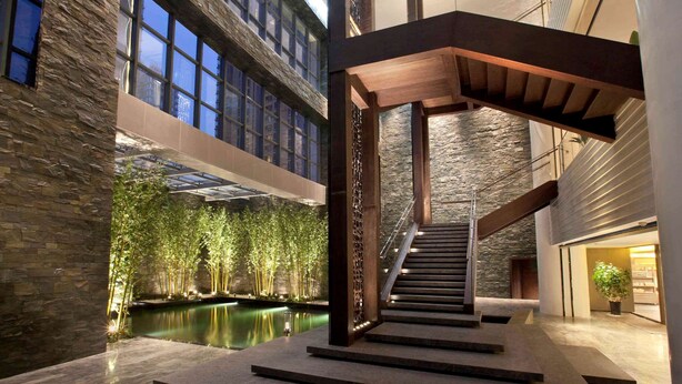 A modern interior with a central staircase, a pool, and a high ceiling with skylights. - Banyan Tree Tianjin Riverside (Tianjin)