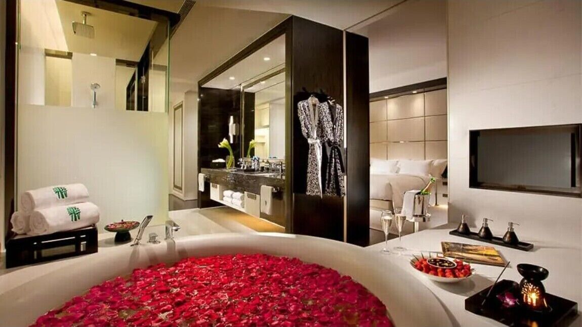 A modern bathroom with a large bathtub, a mirror, a robe, and a sink.