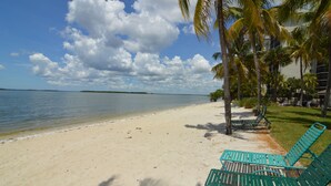 A beach with clear skies, calm water, and green lounge chairs. - Resort Harbour Properties (Fort Myers)