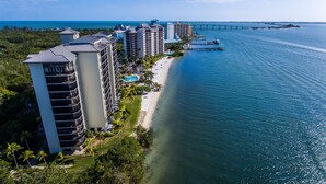 A coastal hotel with multiple high-rise buildings, a beach, and a pier extending into the water. - Resort Harbour Properties (Fort Myers)