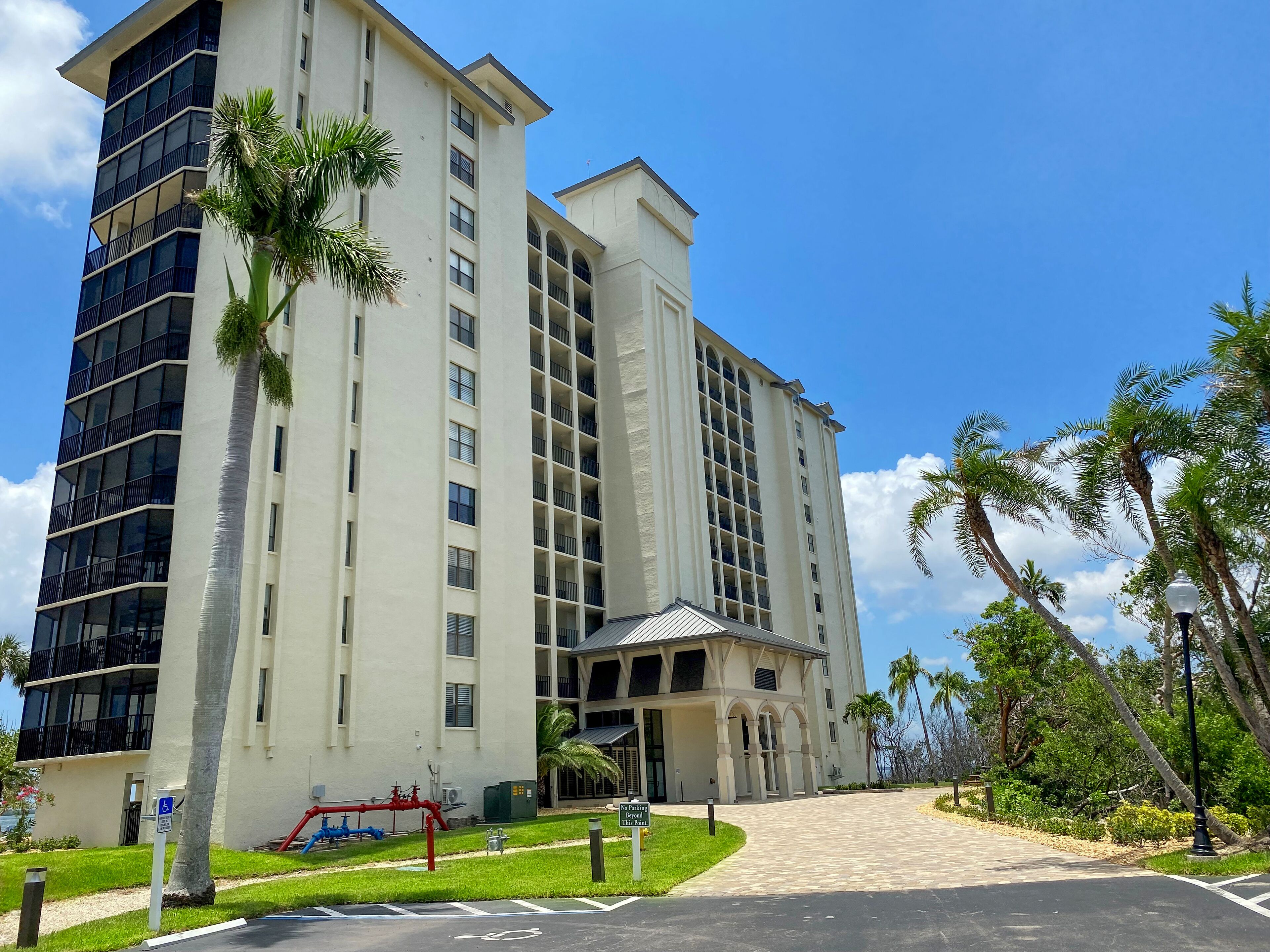 A multi-story hotel with a central courtyard, palm trees, and a no parking sign.
