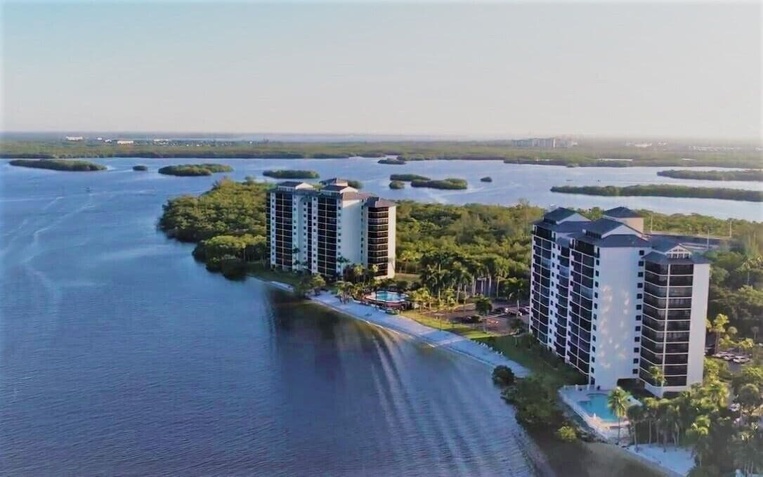 A high-rise hotel with multiple floors, situated by a body of water with several small islands in the background.