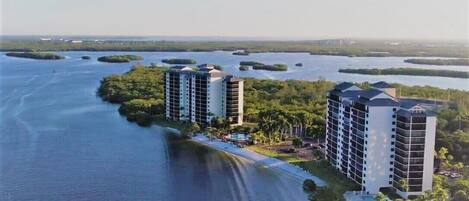 A high-rise hotel with multiple floors, situated by a body of water with several small islands in the background.