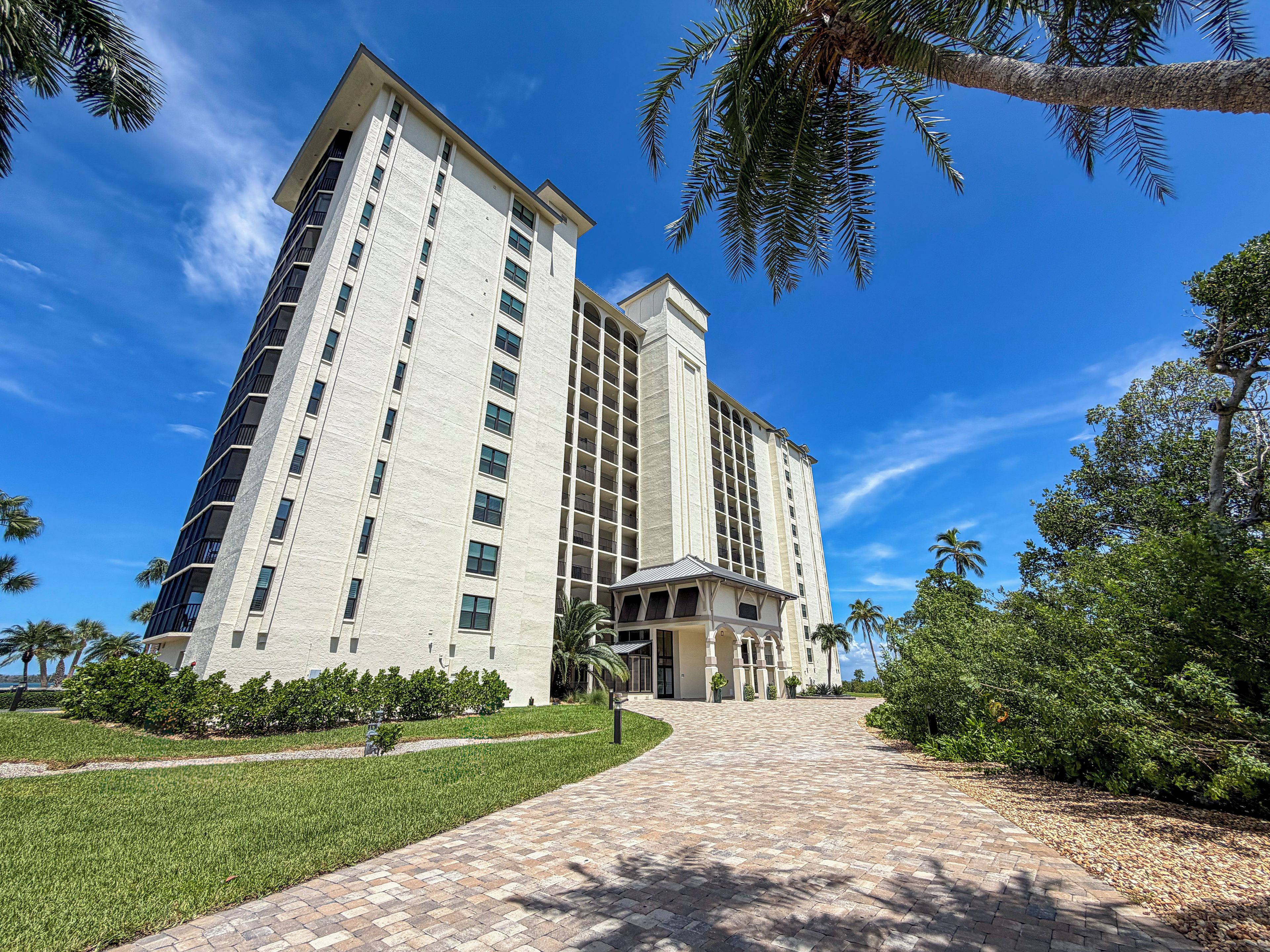 A multi-story hotel with a central courtyard and a paved walkway leading to the entrance.