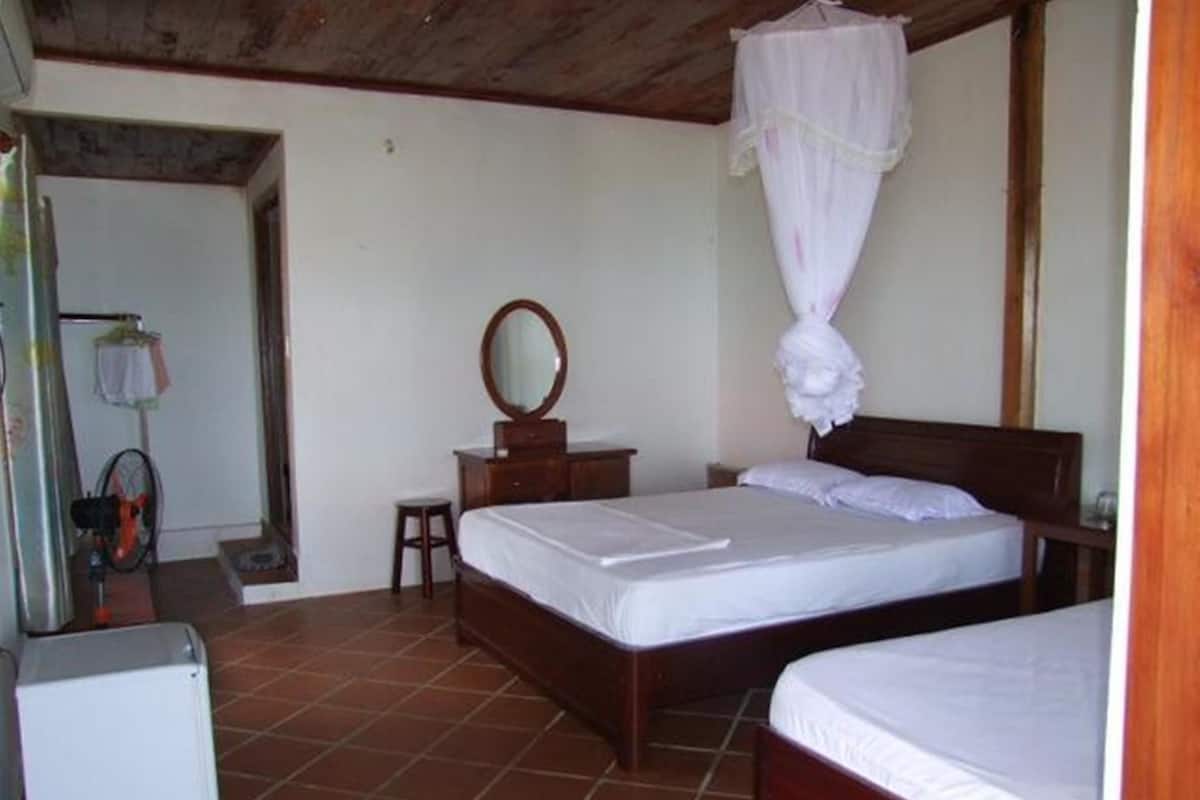 A bedroom with two beds, a wooden headboard, a nightstand, a mirror, and a small stool.