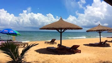 En la playa, arena blanca, sillas reclinables de playa, sombrillas