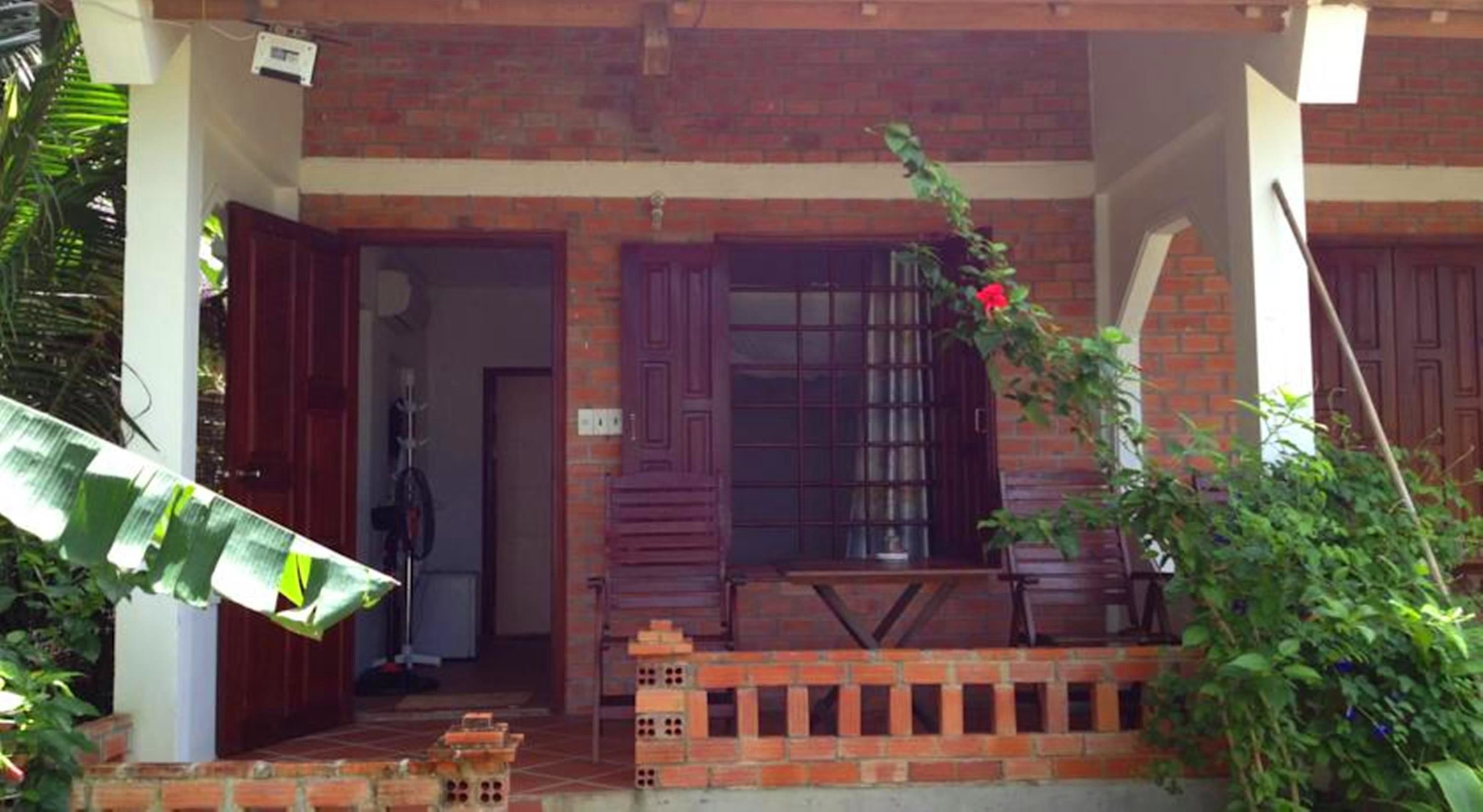 A brick house with a porch, a wooden door, and a window.