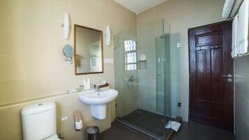 Un baño moderno con ducha de vidrio, lavamanos y inodoro.