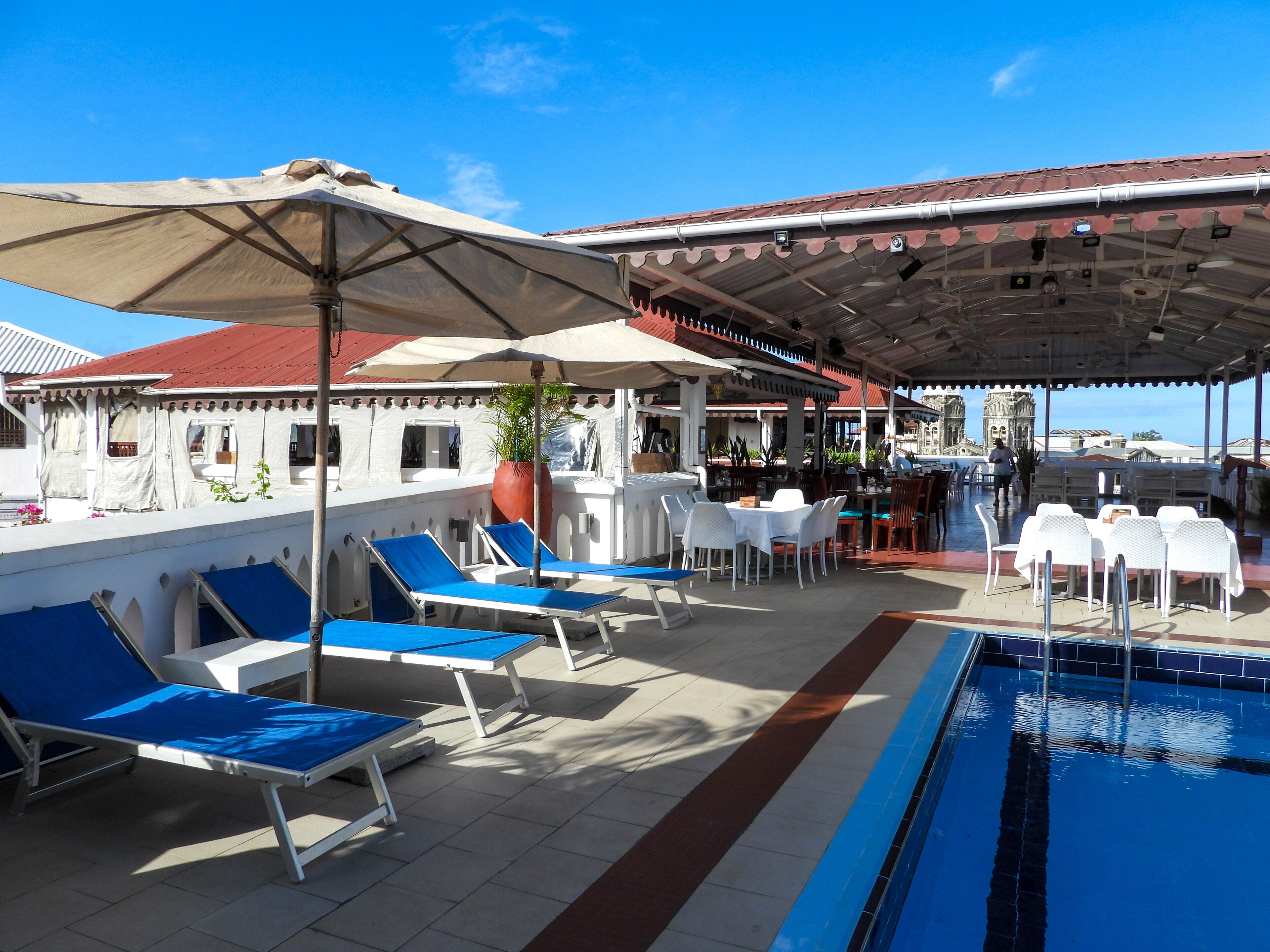 Un espace aménagé au bord de la piscine, avec des chaises longues, des parasols et un bar.