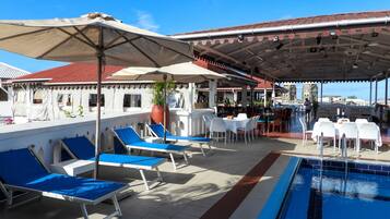 A poolside area with lounge chairs, umbrellas, and a bar.