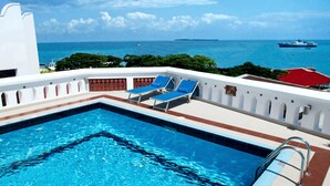 A pool area with a view of the sea, a lifeguard chair, and a no diving sign. - Maru Maru Hotel (Zanzibar Town)