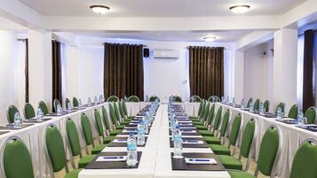 Ein Konferenzraum mit langem Tisch, grünen Stühlen, Wasserflaschen und einer weißen Tischdecke.