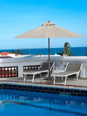 Una piscina al aire libre, sombrillas, tumbonas