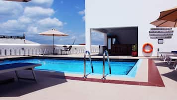 Alberca al aire libre, sombrillas en la alberca y camastros