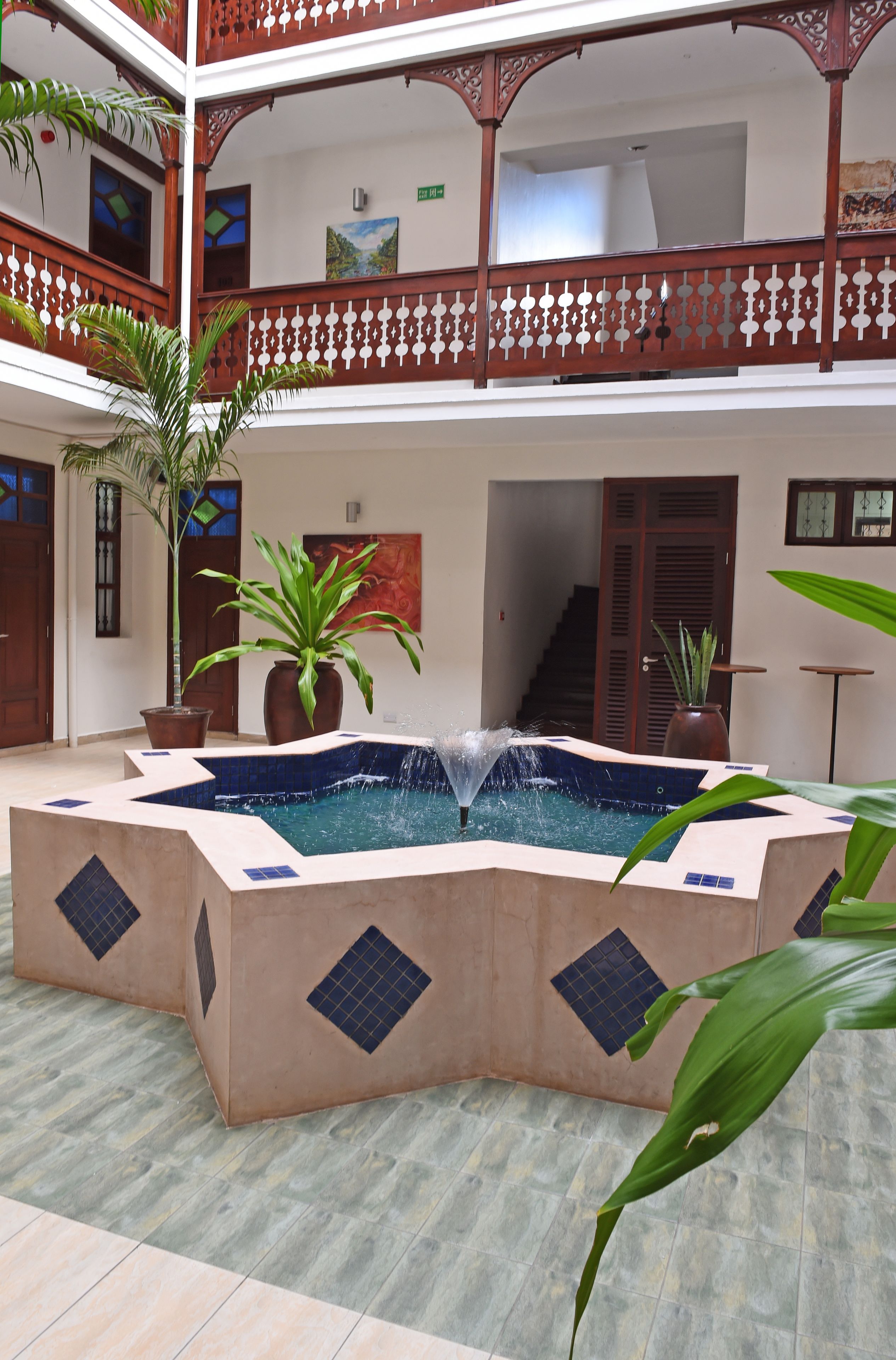 A courtyard with a central water feature, potted plants, and a staircase leading to an upper level.
