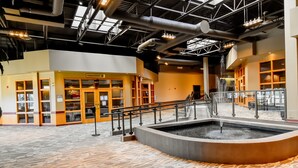 A spacious indoor area with a central water feature, a reception desk, and a staircase leading to upper levels. - Canad Inns Destination Centre Windsor Park (Winnipeg)