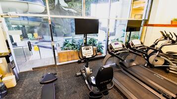 Un gimnasio con equipo cardiovascular, cinta de correr y máquina de remo.