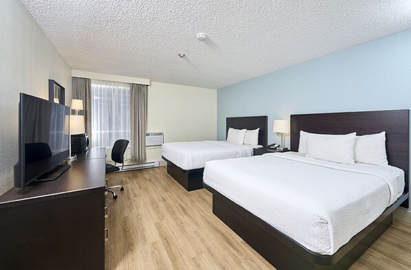 A hotel room with two beds, a desk with a computer, a TV, and a window with curtains. - Canad Inns Destination Centre Windsor Park (Winnipeg)