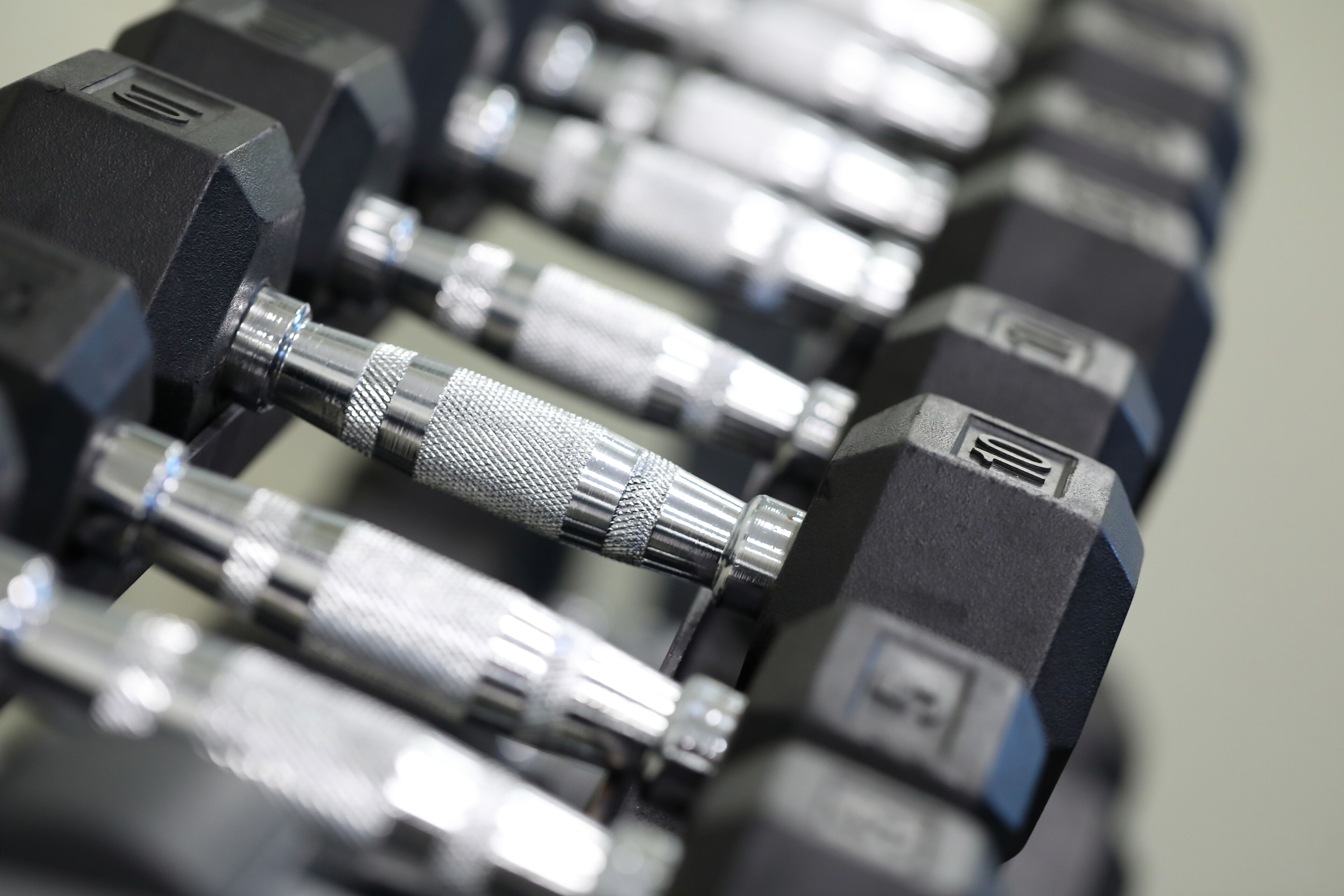 A close-up of a row of black dumbbells with metallic handles and weight markings.