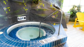 A hot tub with a tiled edge, a sign reading "0.84 M", and a yellow chair in the background. - Canad Inns Destination Centre Windsor Park (Winnipeg)