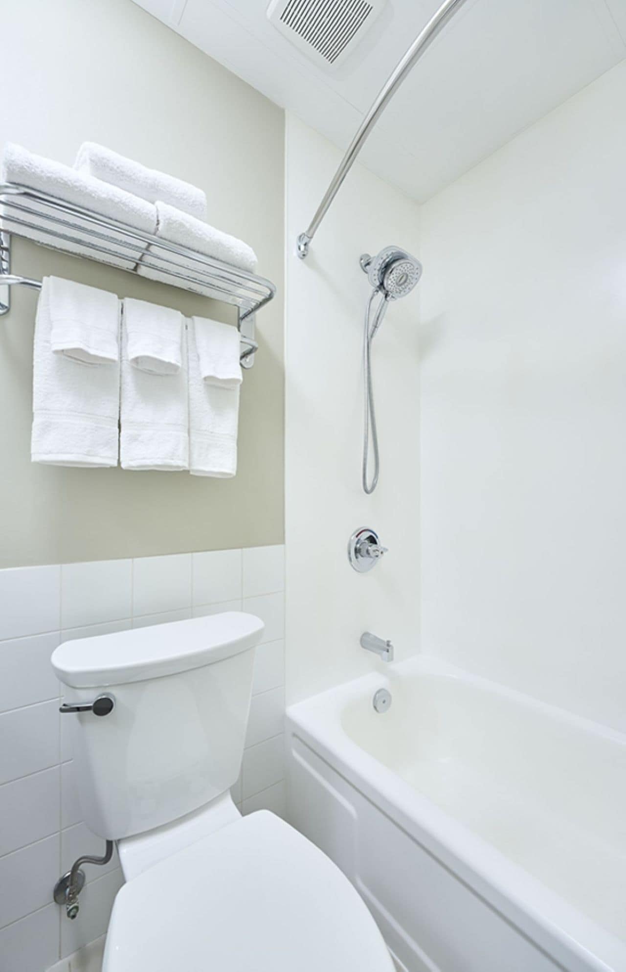 A modern bathroom with a toilet, sink, and bathtub. There are towels hanging on a rack above the sink.