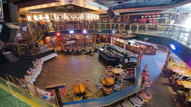 A spacious indoor venue with multiple seating areas, a stage, and a bar. - Canad Inns Destination Centre Windsor Park (Winnipeg)
