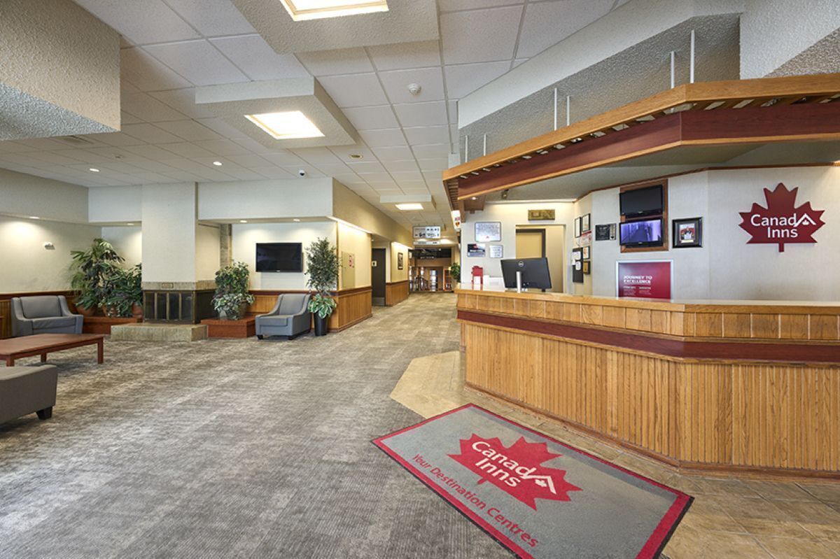 L’aire d’accueil du Canada Inn comprend un comptoir de réception en bois, un espace salon et une cheminée.