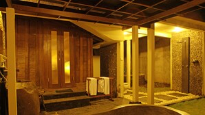 A spa area with a large bathtub, wooden steps leading to a wooden door, and a stone wall. - KajaNe Tulamben (Kubu)