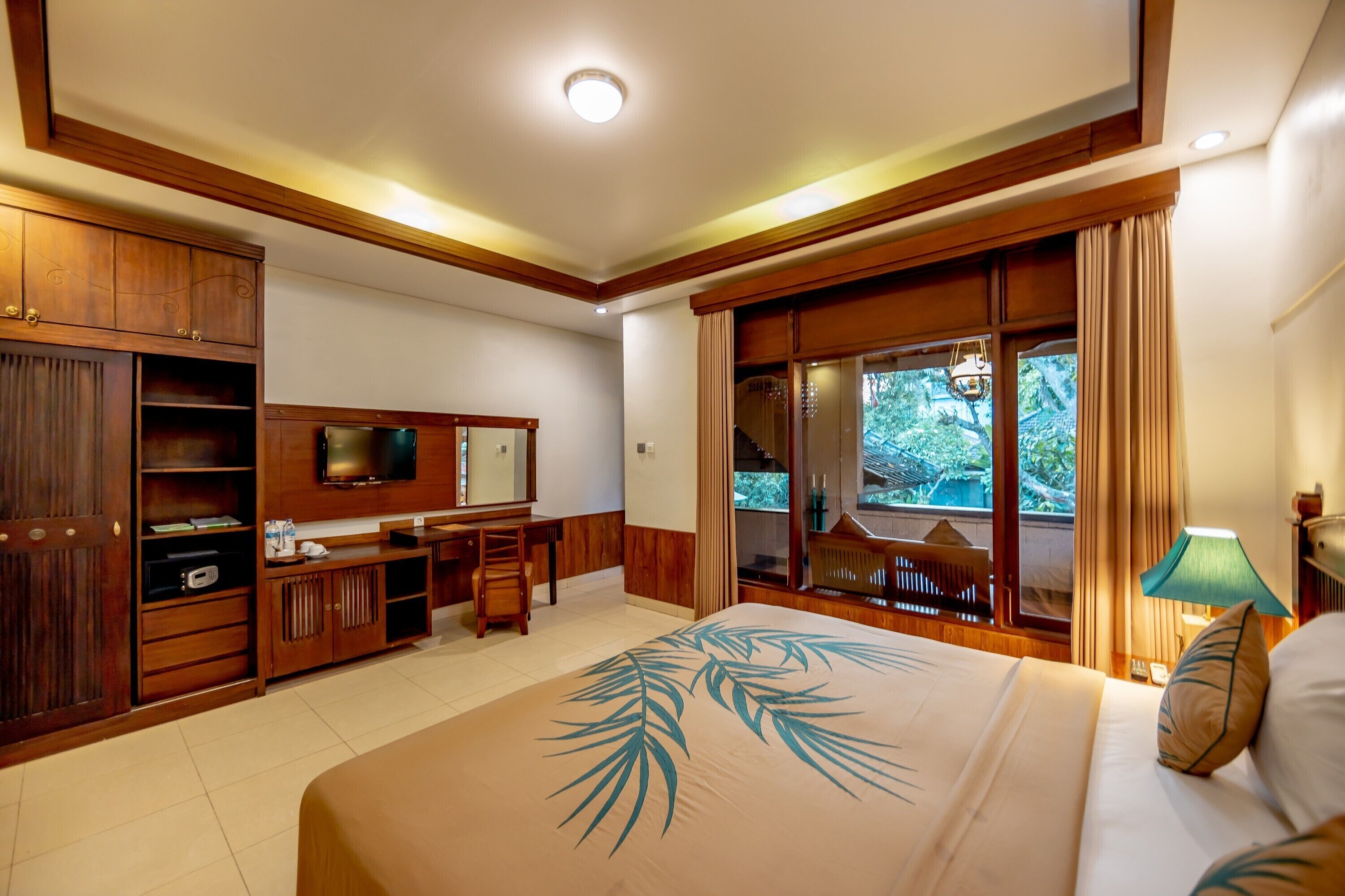 Una habitación de hotel con una cama grande, muebles de madera, televisión y vistas al exterior.