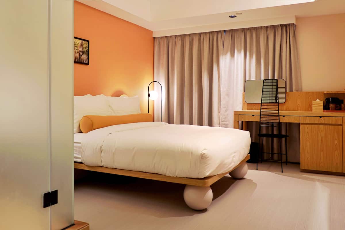 A hotel room with a bed, a desk, and a chair.