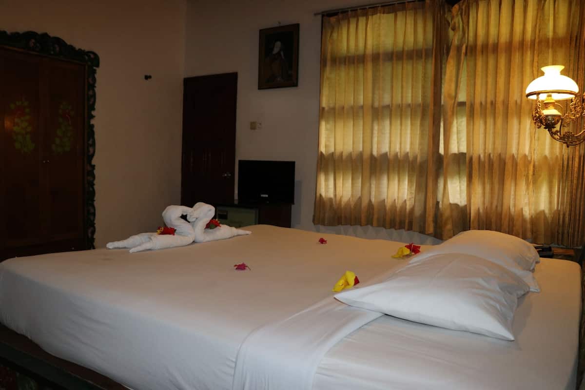 A hotel room with a bed, a wardrobe, a television, and a window with curtains.