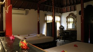A room with two beds, a wooden desk, a mirror, and a window with curtains. - Puri Bunga Senggigi (Senggigi)