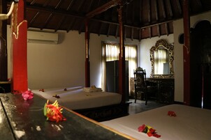 A room with two beds, a wooden desk, a mirror, and a window with curtains.