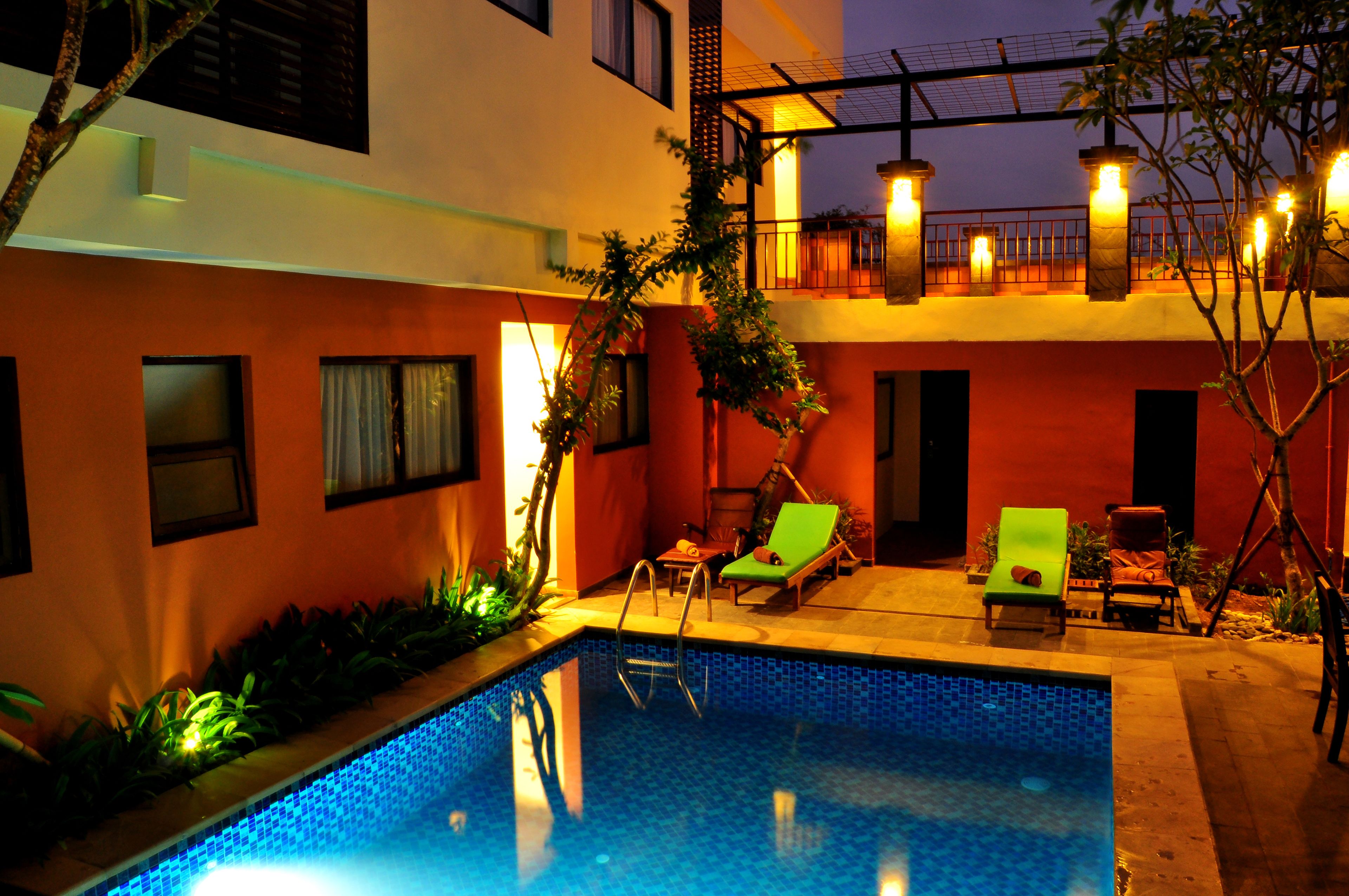 A swimming pool with lounge chairs, a small table, and a staircase leading to an upper level.