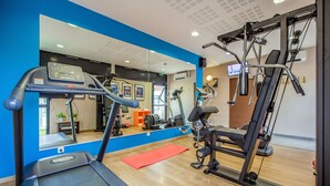 A gym with treadmills, exercise equipment, a red mat, and a large mirror. - Appart'City Confort Grenoble Inovallée (Montbonnot-Saint-Martin)