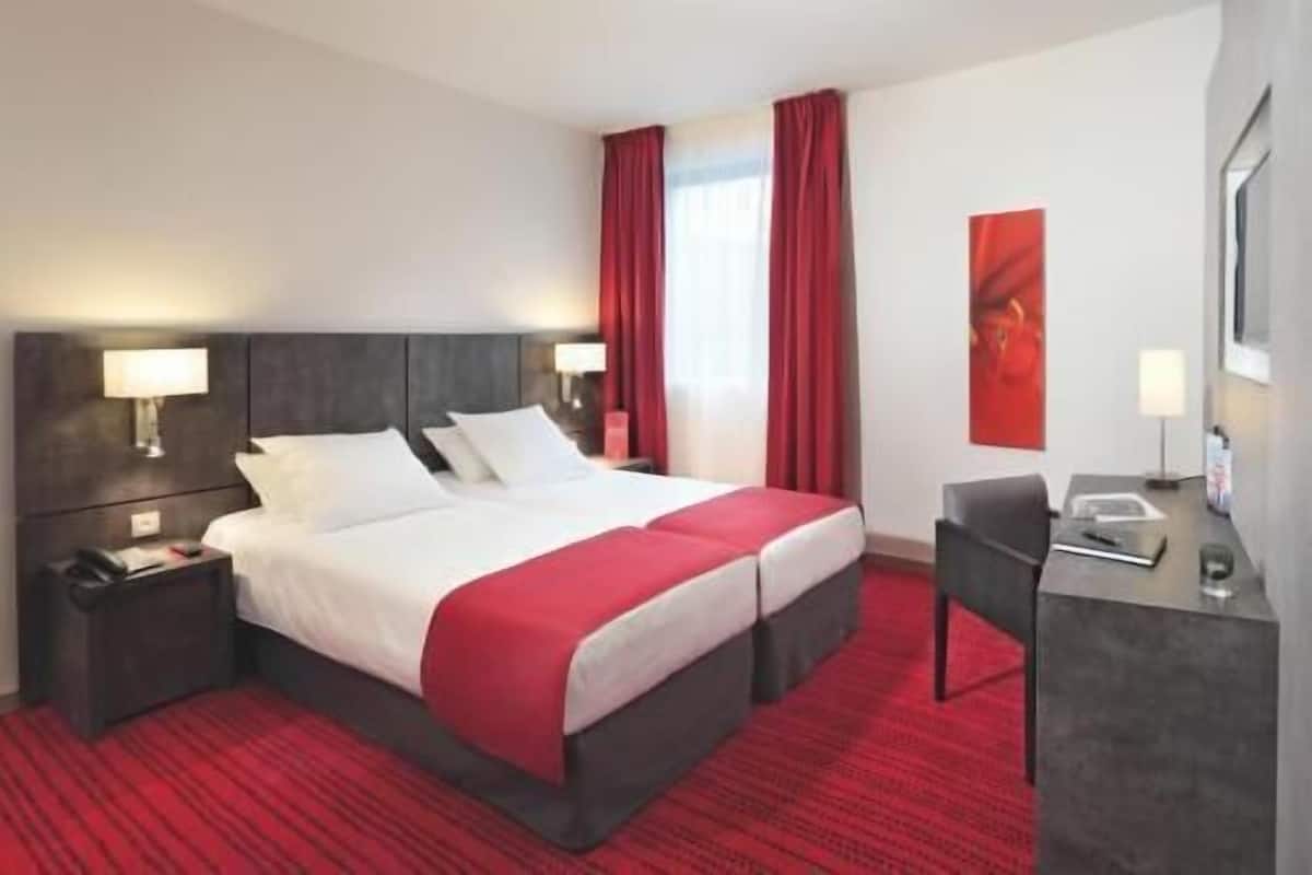 Hotellihuone, jossa on sänky, kaksi yöpöytää, työpöytä ja tuoli.