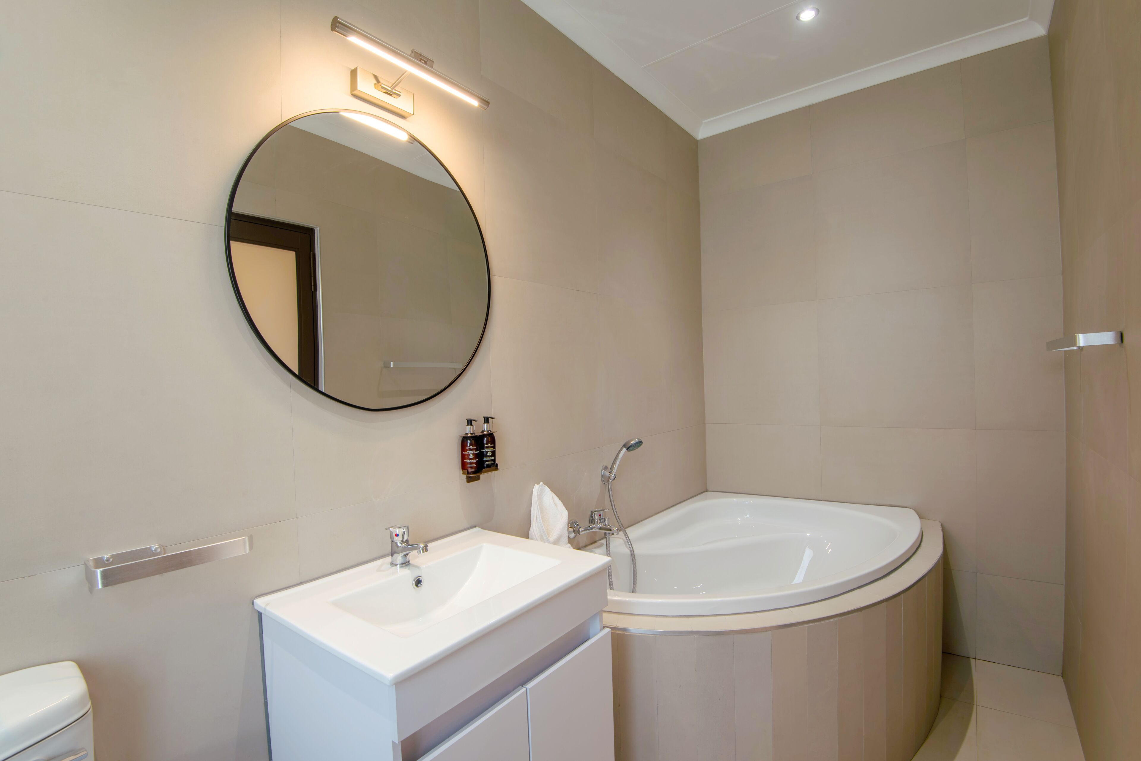 A modern bathroom with a round mirror, a sink, and a freestanding bathtub.