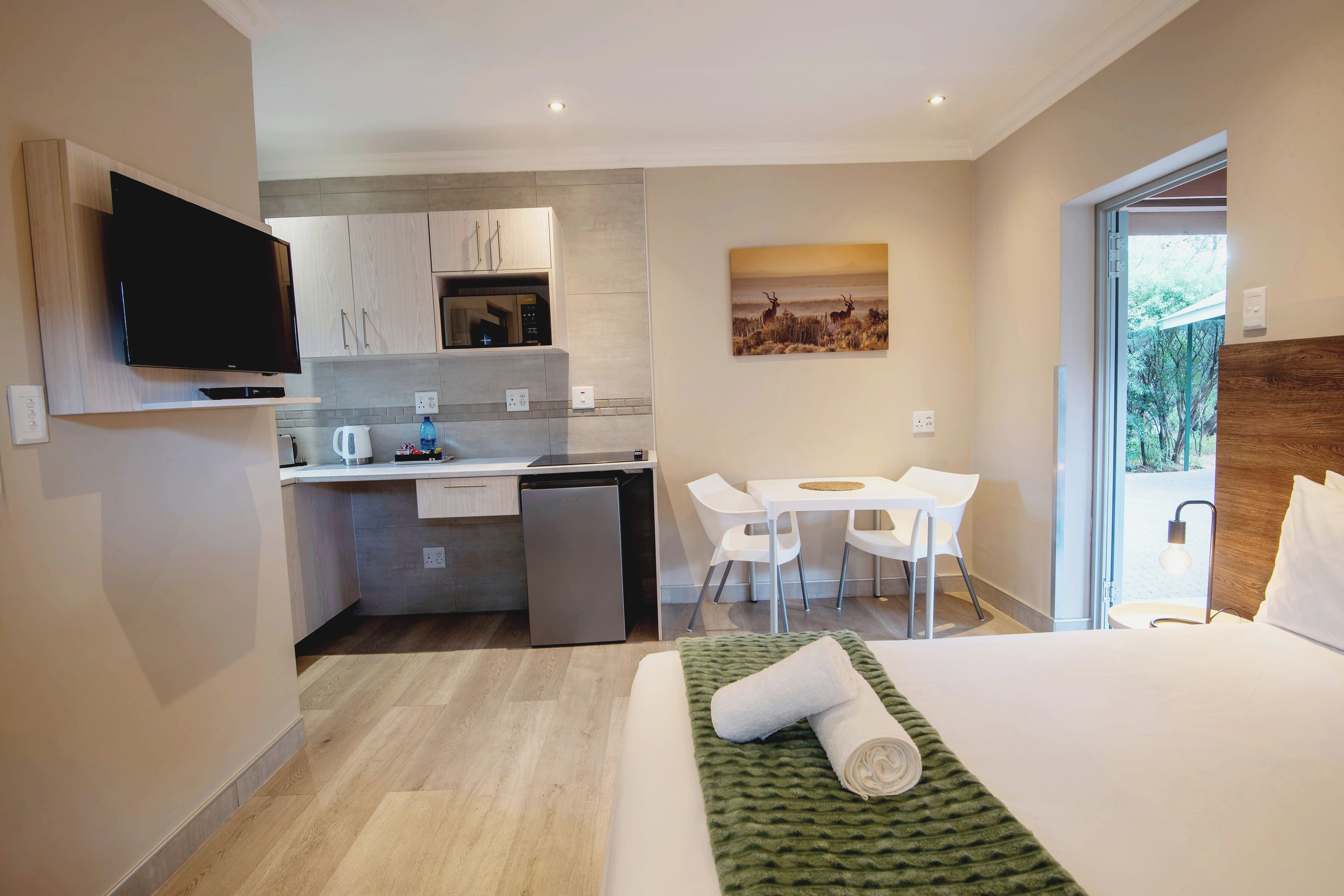 Una habitación de hotel moderna con cama, escritorio, kitchenette y televisión.