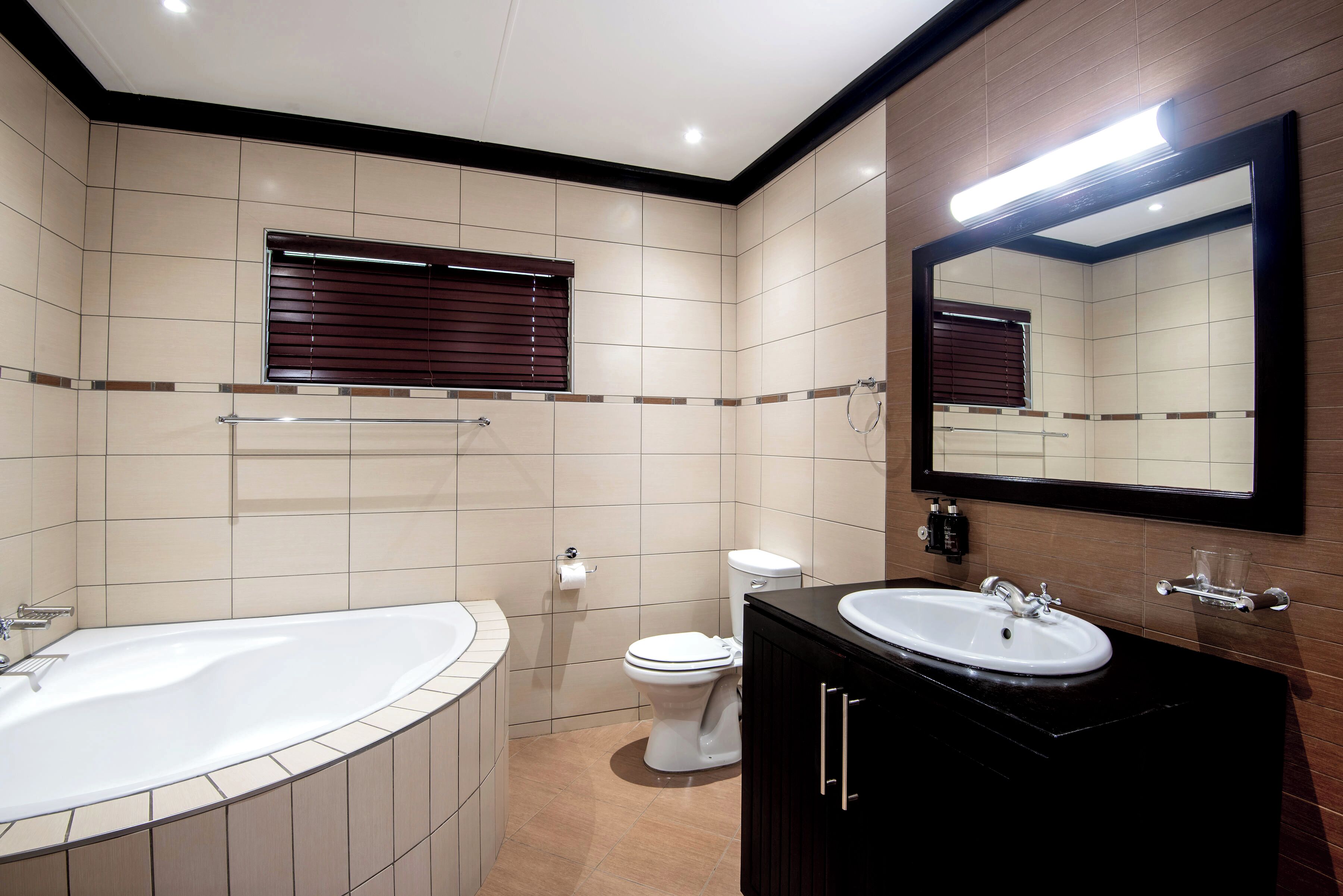 Un baño moderno con una bañera independiente, un inodoro y un lavamanos con espejo.