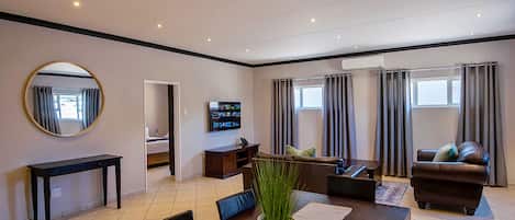 Una sala de estar moderna con una mesa de comedor, sofá, televisor y un espejo grande.