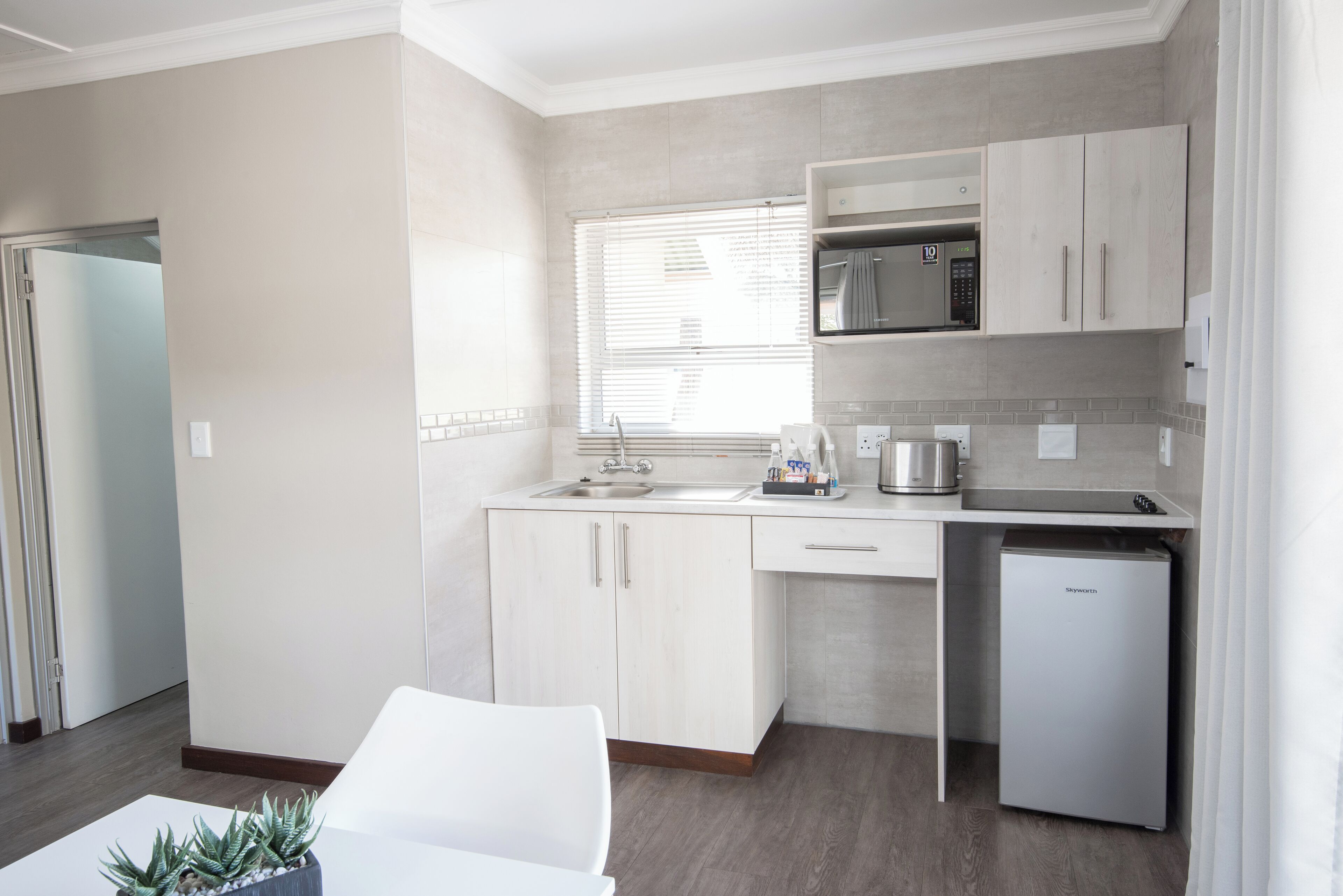 A modern kitchen with white cabinetry, a built-in microwave, and a compact dishwasher.