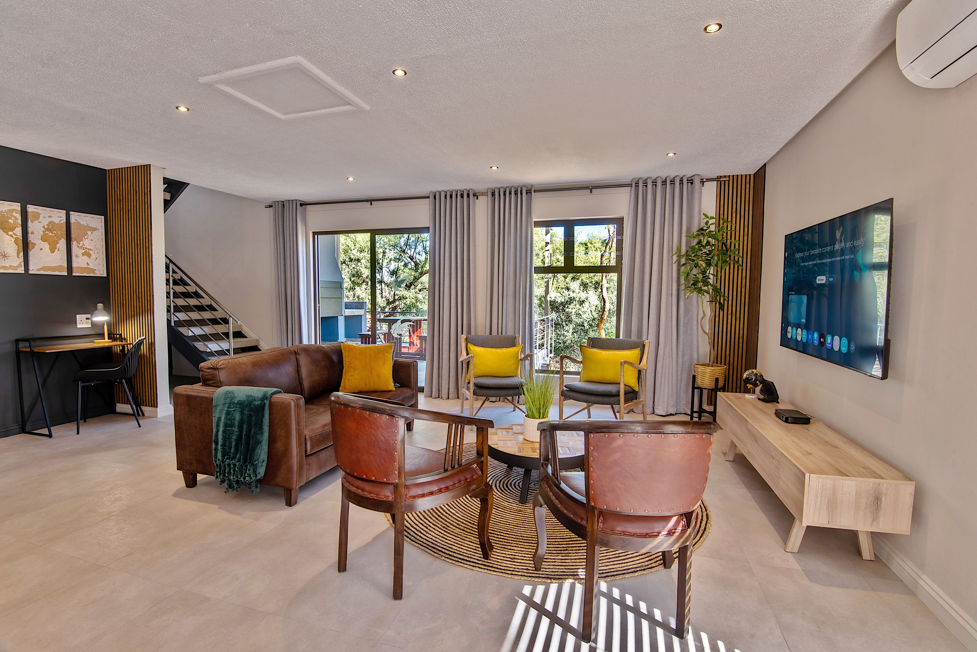 A modern living room with a sofa, chairs, a coffee table, and a TV.
