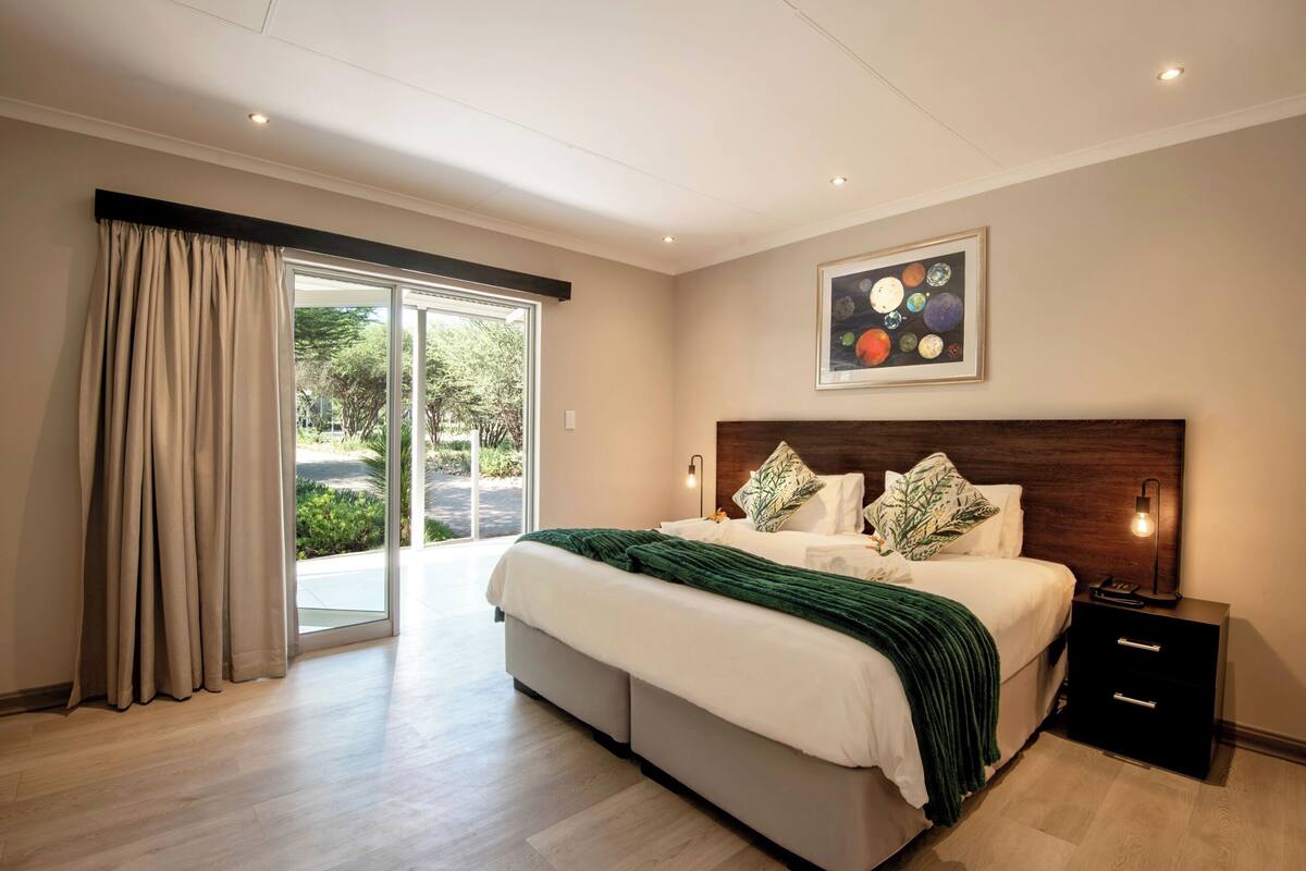 Une chambre à coucher moderne avec un grand lit, une table de chevet, une lampe fixée au mur et un tableau représentant des planètes.